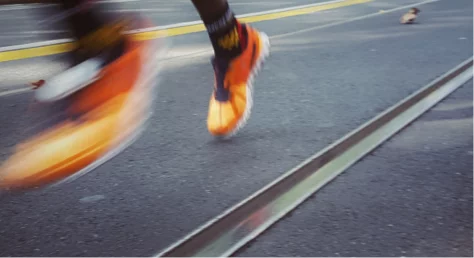 Close-up of a person running on a road with blurred motion effect