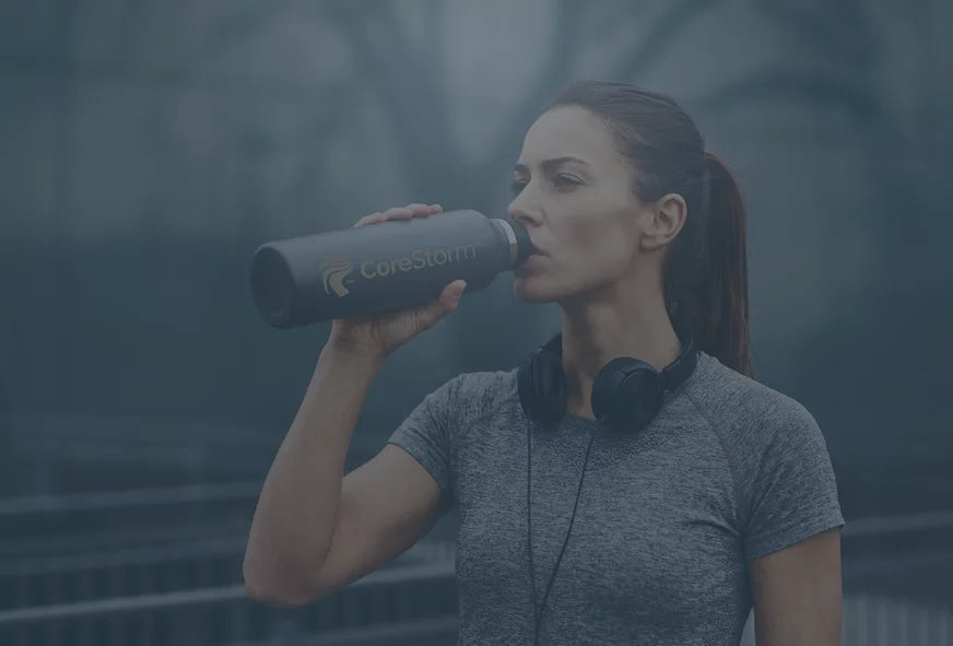 Woman drinking from a CoreStorm water bottle with a blurred background